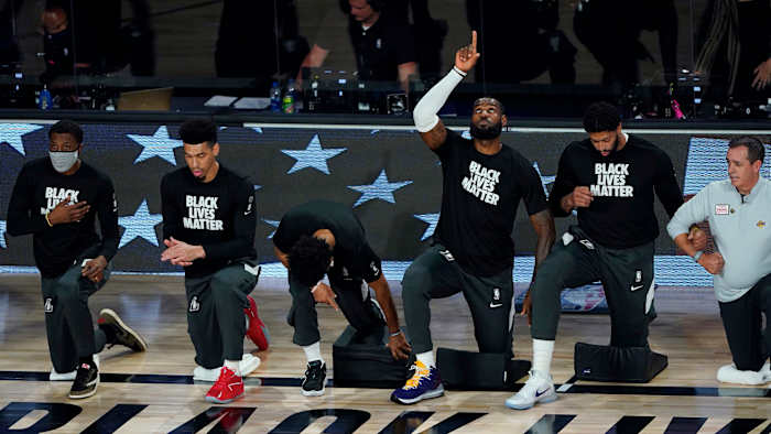 Los Angeles Lakers' LeBron James (23) points upwards while kneeling with teammates prior to facing the Denver Nuggets in the first half of an NBA basketball game Monday, Aug. 10, 2020, in Lake Buena Vista.